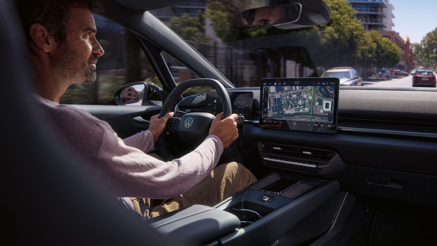 Egy férfi egy VW ID.3 Neo modellt vezet, a központi kijelzőn megjelenő online navigáció útmutatásait követve.