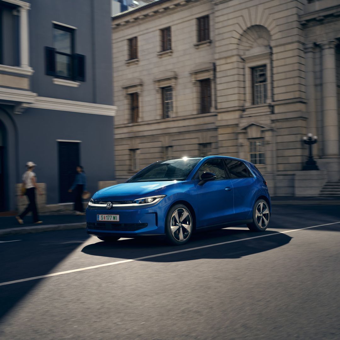 Ein blauer VW ID. Polo Style fährt durch eine Stadt.