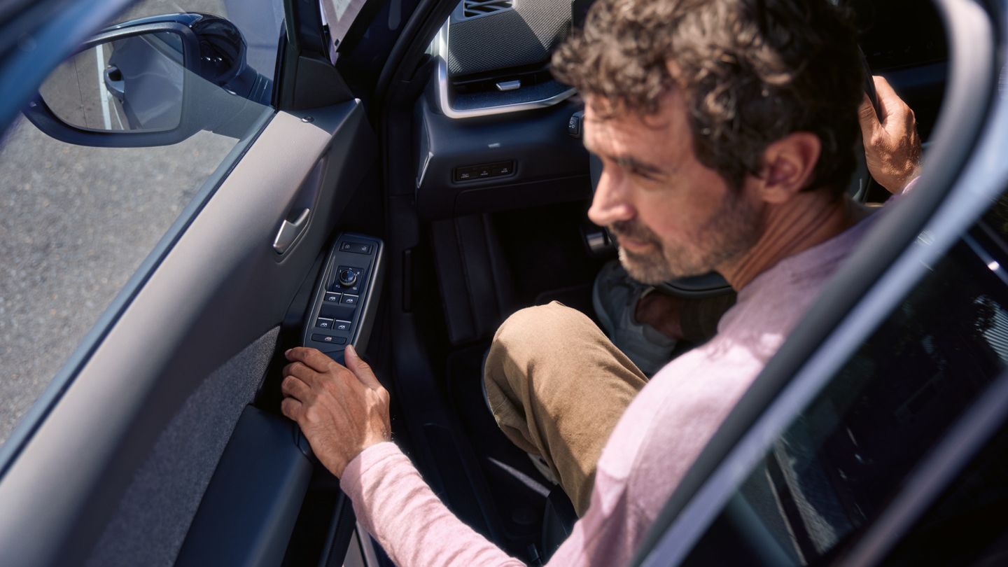 Egy férfi egy VW ID.3 Neo modellben. A négy ablakemelő gombbal ellátott vezetőoldali ajtó félig nyitva van. 