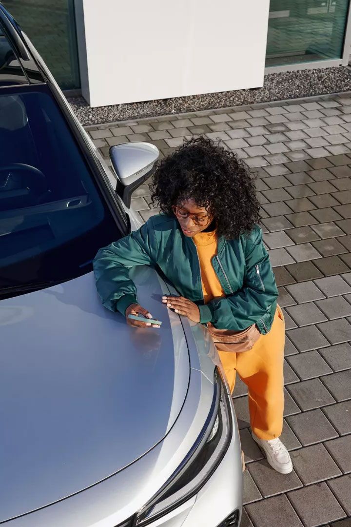 Ein VW ID. mit Blick von oben, eine Frau lehnt an der Kühlerhaube