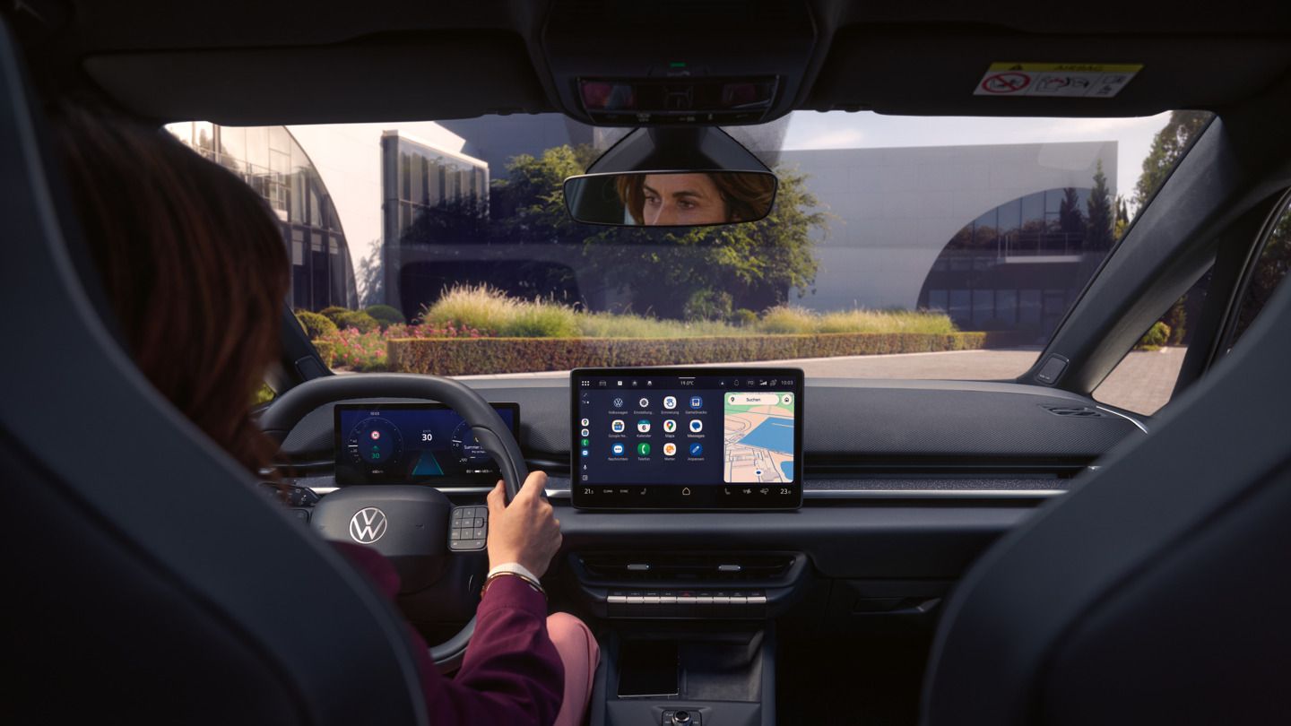 Egy nő a vezetőoldal felől megérinti a központi kijelzőt egy VW ID.3 Neo modellben. 