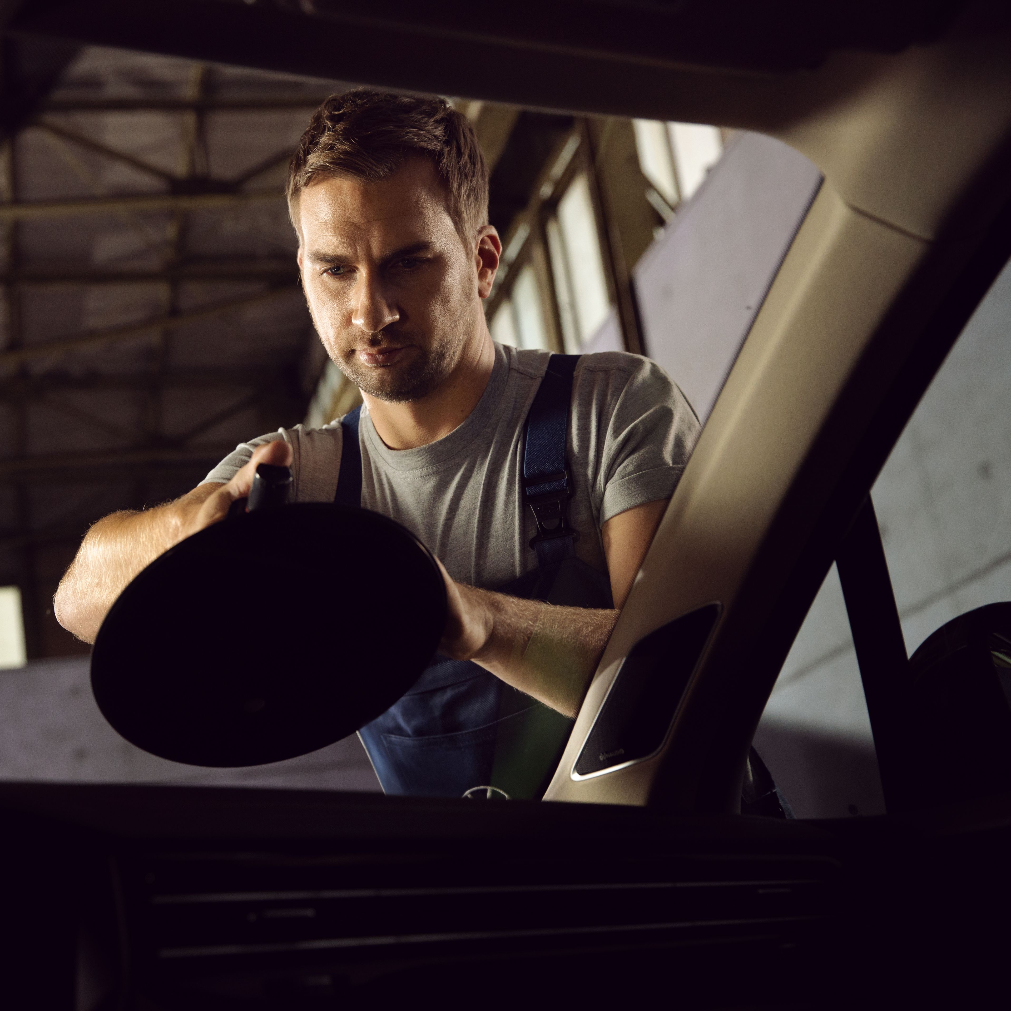 Szerelő férfi a szélvédő előtt