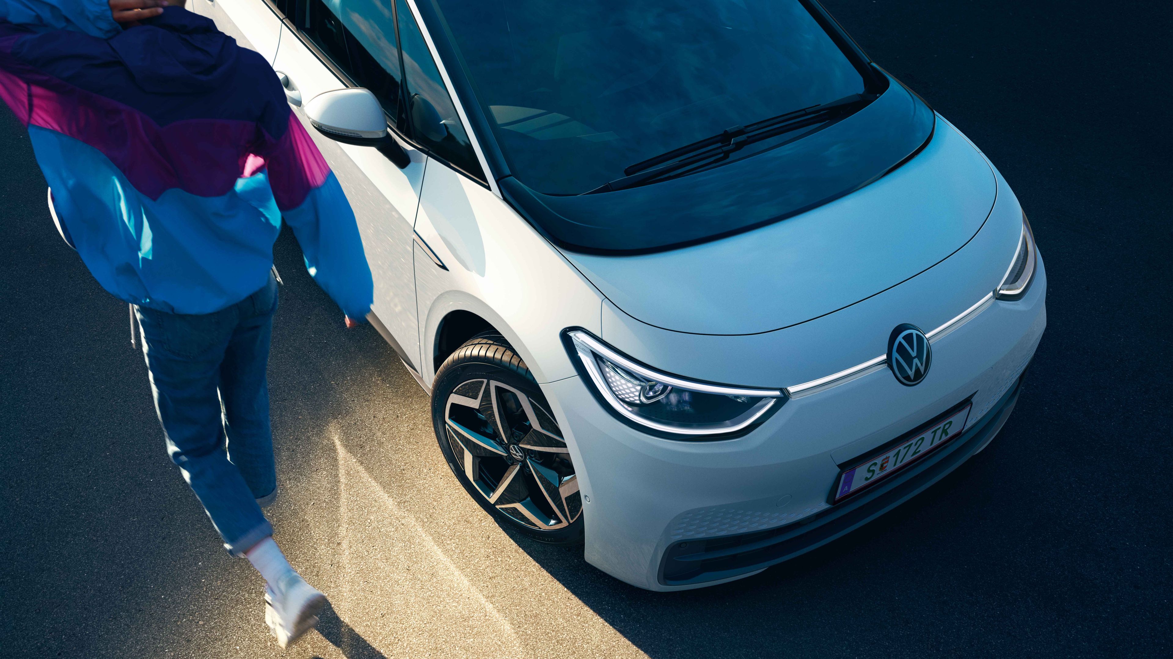 Zu sehen ist eine Frau die vor einem VW e-up! steht und diesen gerade auflädt. 