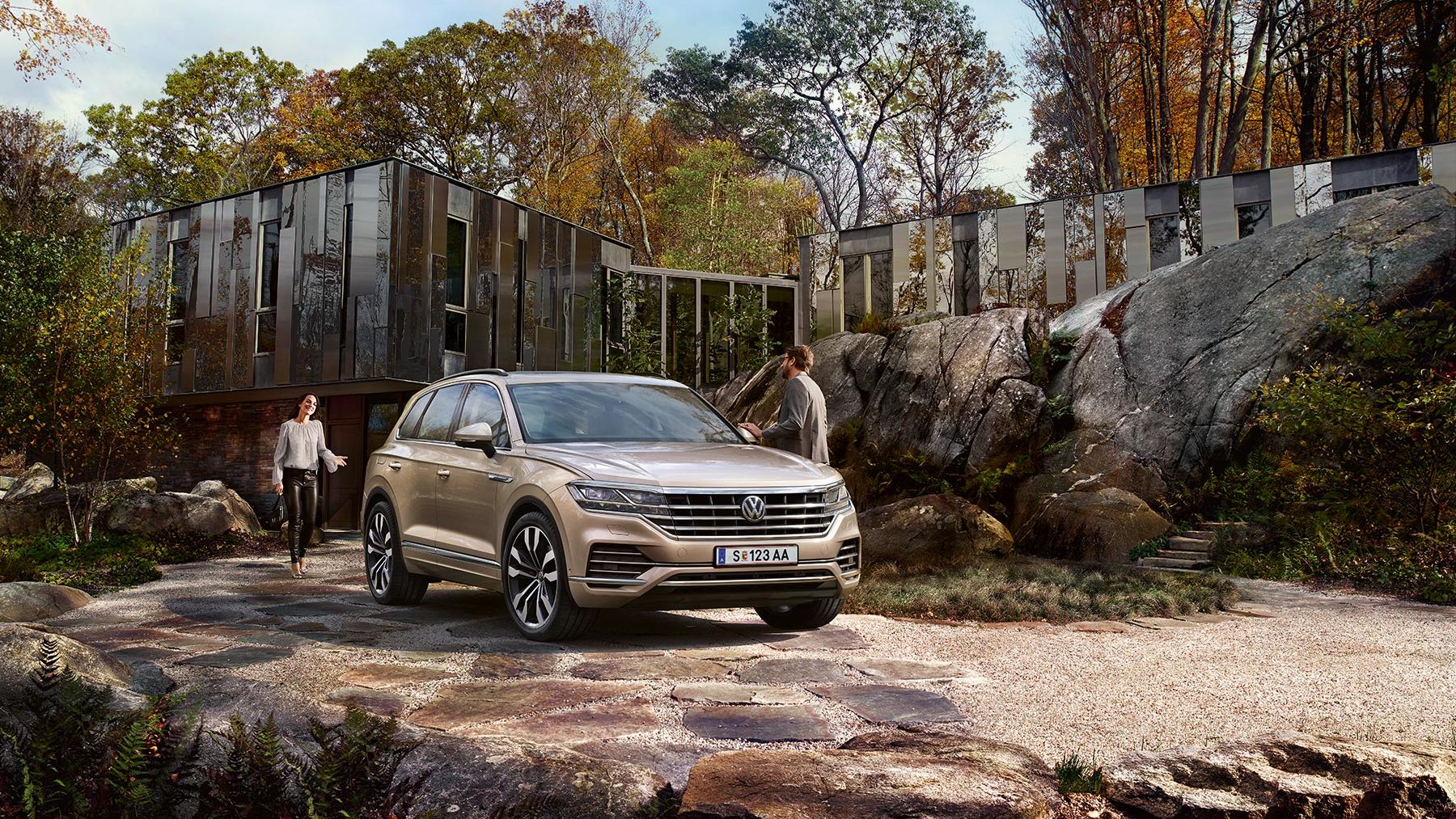 Ein VW Touareg steht geparkt in einer Einfahrt vor einem Haus, umgeben von großen Steinen 