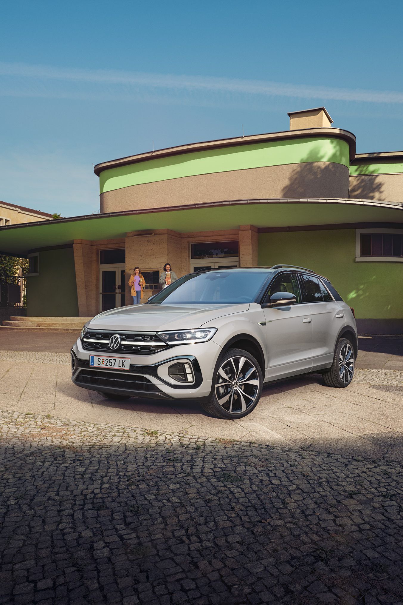 VW T-Roc R-Line in weiß vor einem Gebäude, Front und Seite sichtbar