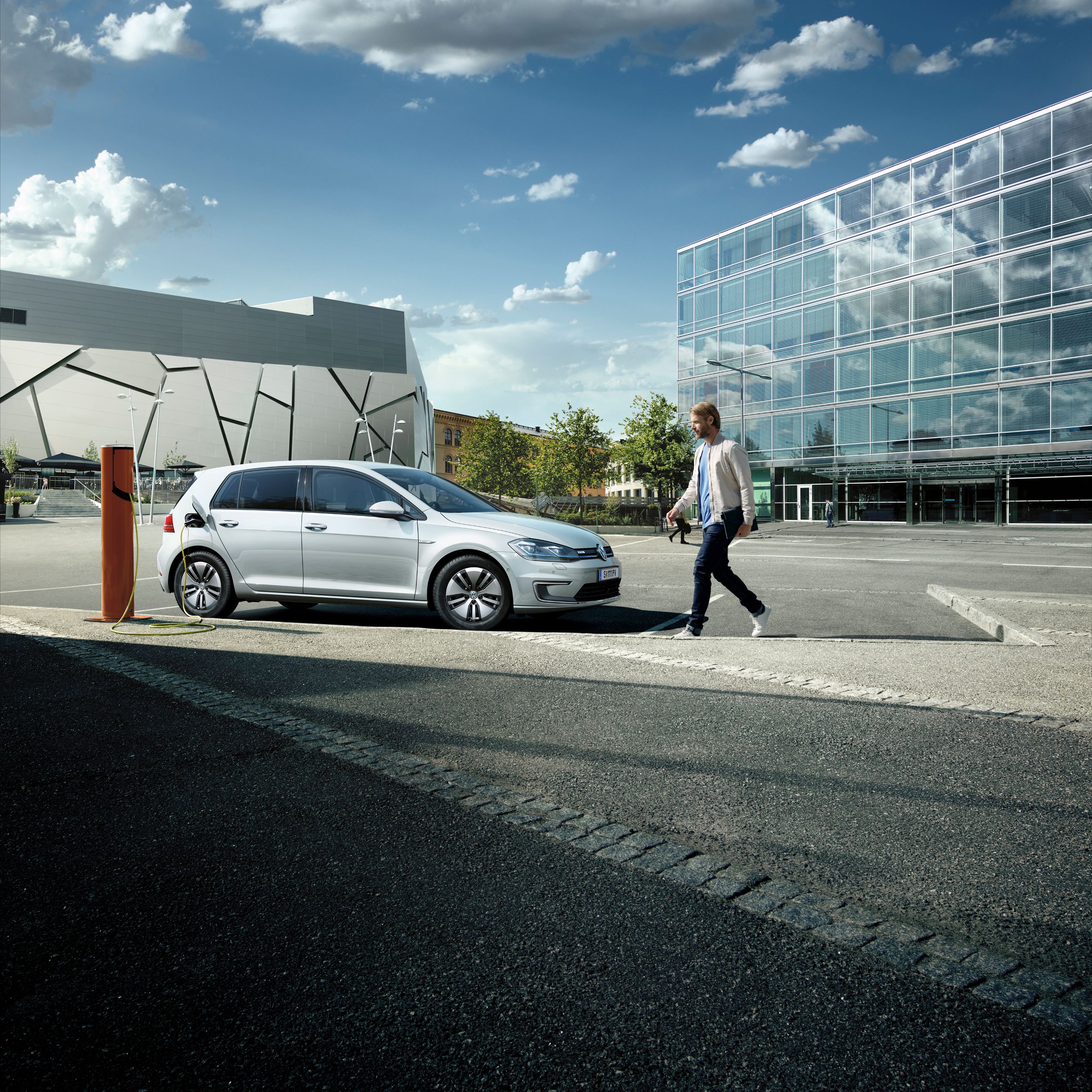 VW Golf töltés közben, mellette egy férfi