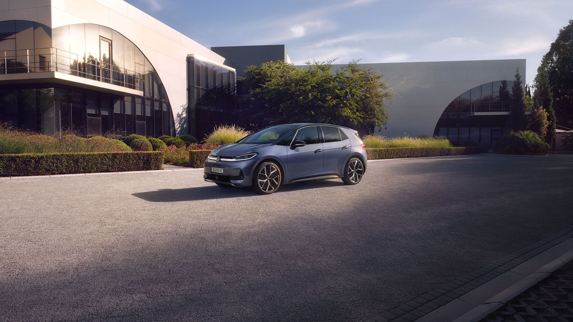 Egy kék VW ID.3 Neo egy modern épület előtt parkol.