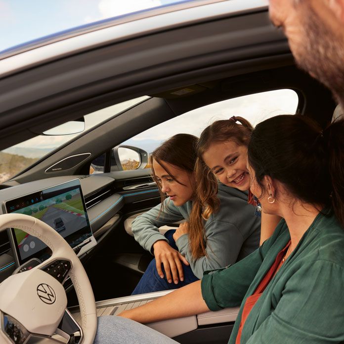 Blick in den geparkten VW ID.7 in dem Familie ein Spiel in der In-Car App spielt