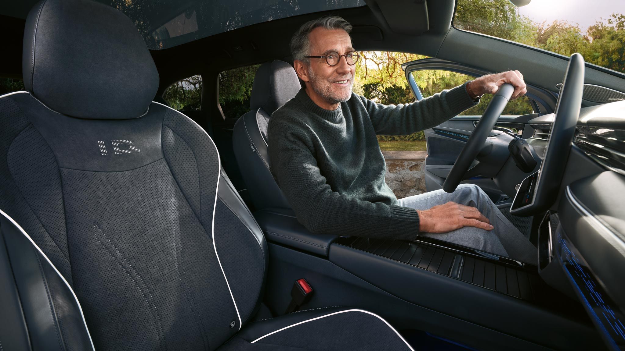 Mann sitzt am Fahrersitz des geparkten VW ID.7 Tourer, die Fahrertür ist geöffnet