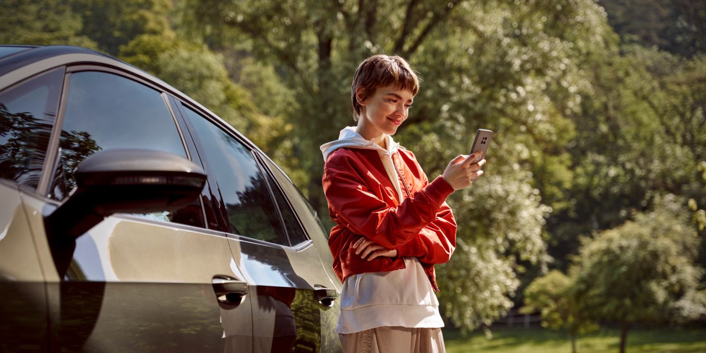 nő egy okostelefonnal áll egy VW modell mellett