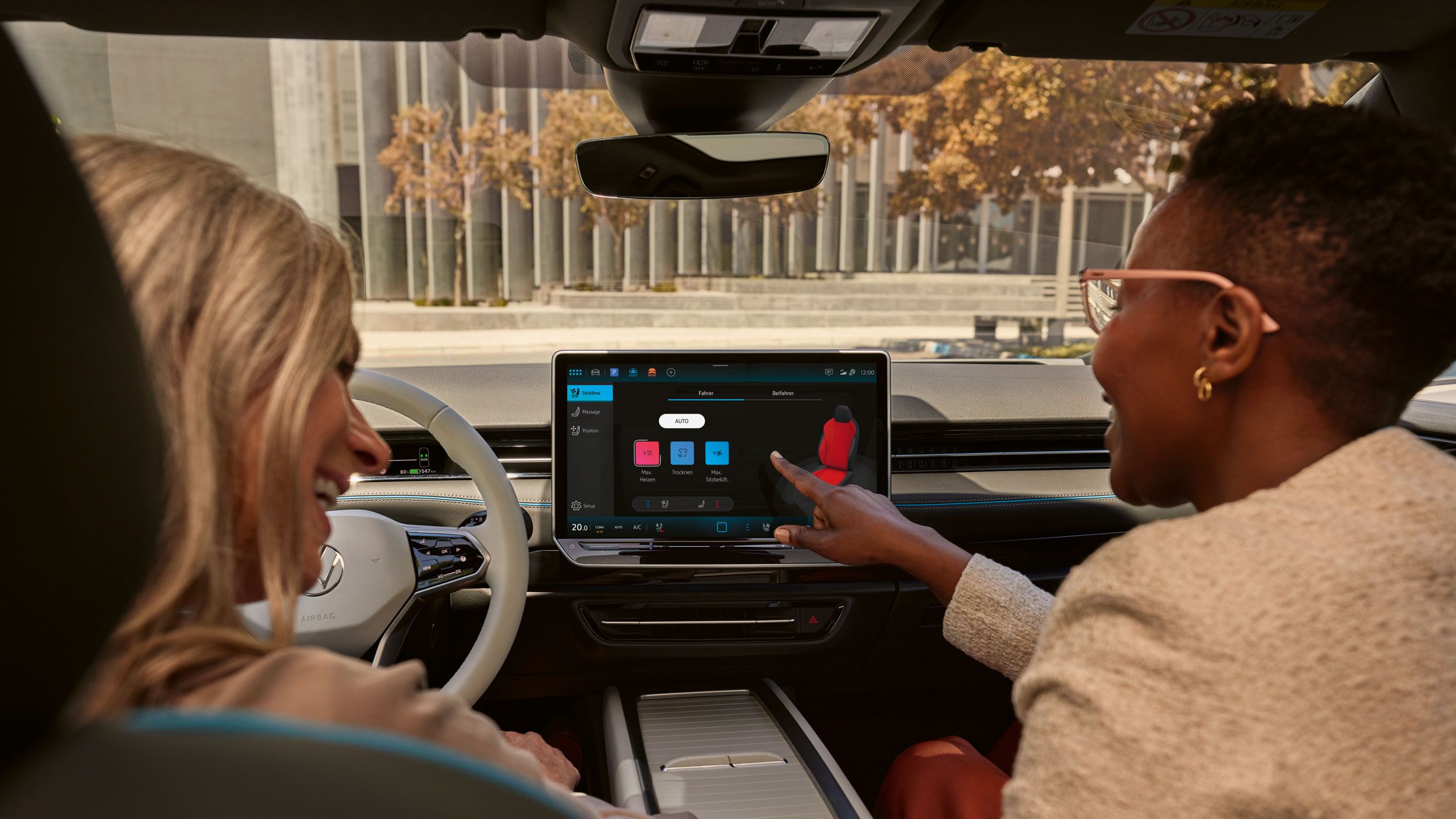 Frau auf ID.7 Beifahrersitz bedient Touch Screen im Fahrzeug