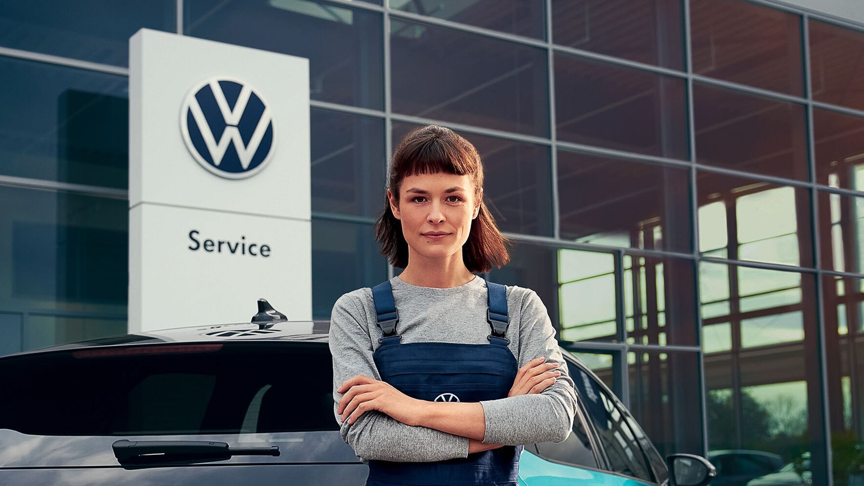 Szerelő nő áll egy VW márkakereskedés előtt