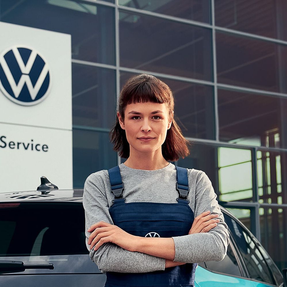 Szerelő nő áll egy VW márkakereskedés előtt