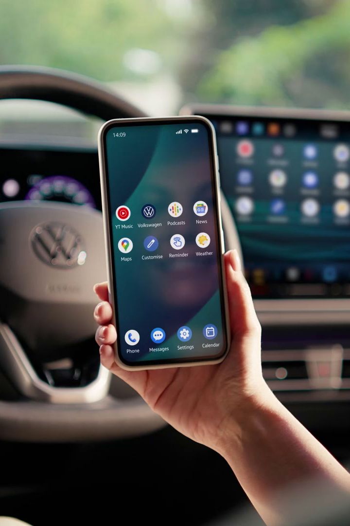 Egy nő ül egy Volkswagen vezetőterében, kezében mobiltelefon.