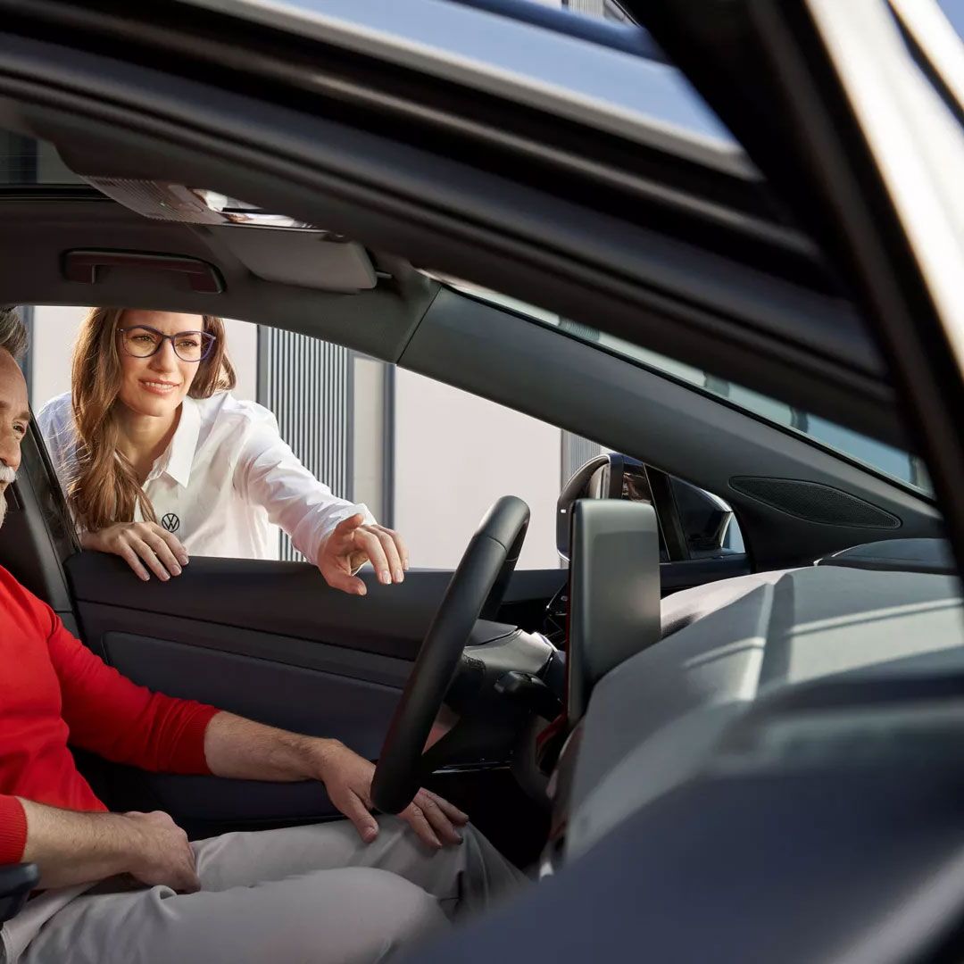 Eine VW Servicemitarbeiterin erklärt einem Kunden die Funktionen des ID.