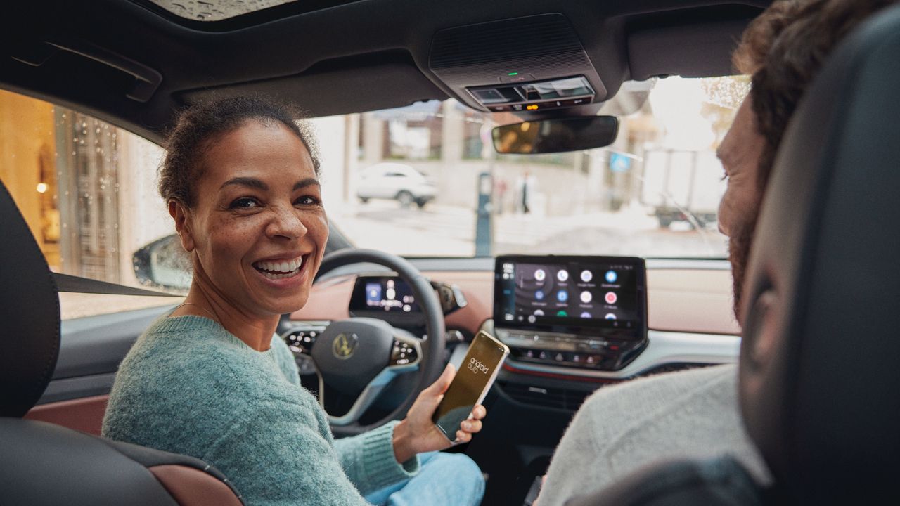 Frau bedient mit Ihrem Smartphone App Connect in Ihrem VW ID.5
