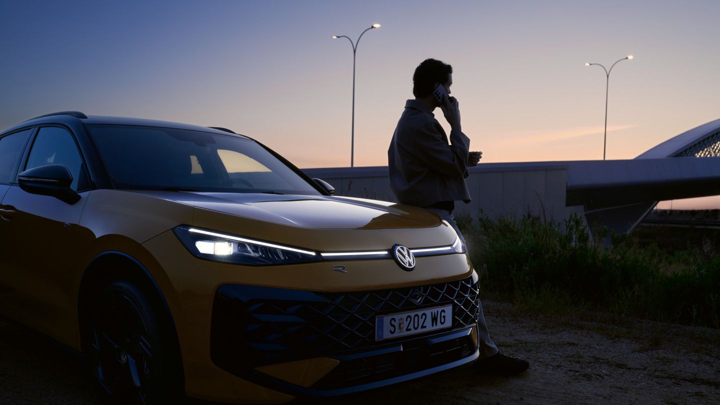 T-Roc fényszórói, az autó mellett egy férfi telefonál